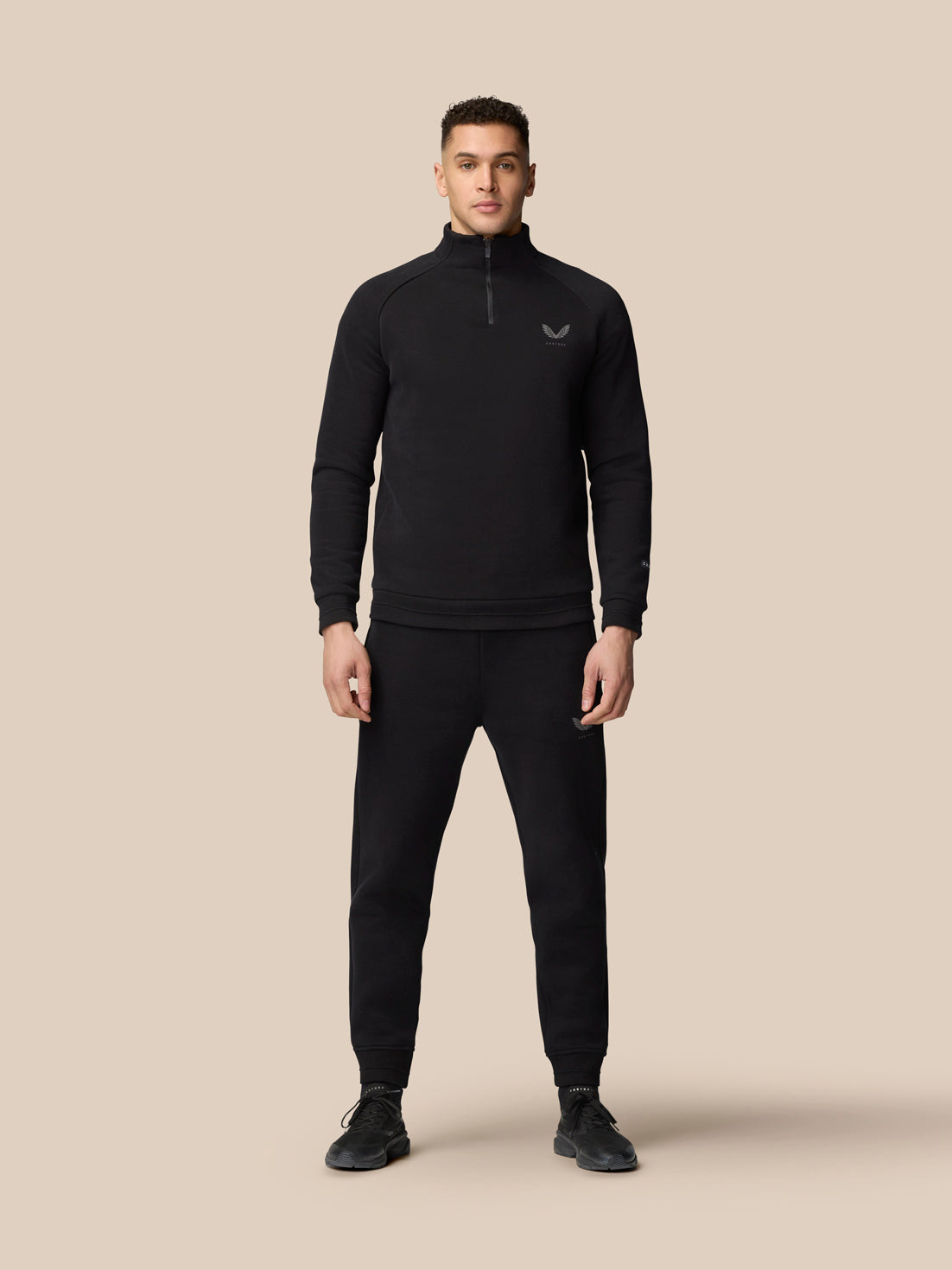 Full body front view of a man wearing black Adapt Fleece Joggers with zip pockets and a drawstring waistband