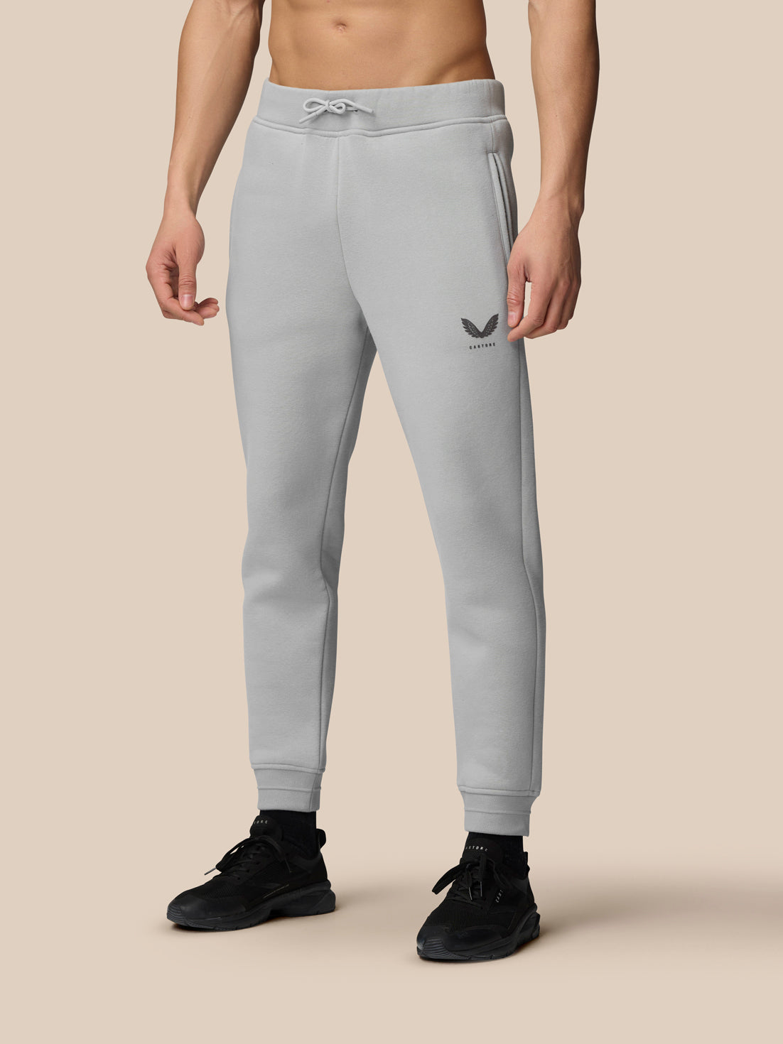 Grey Adapt Fleece joggers on a model with logo on the thigh and cuffed ankles paired with black sneakers
