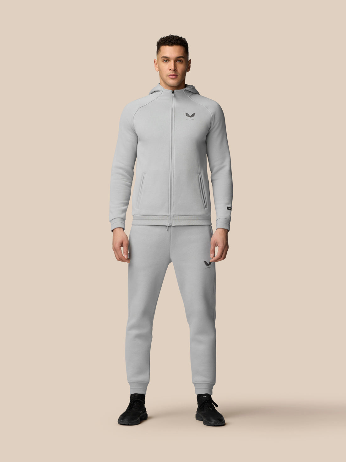 Male model wearing grey Adapt Fleece joggers with zip pockets and drawstring waist