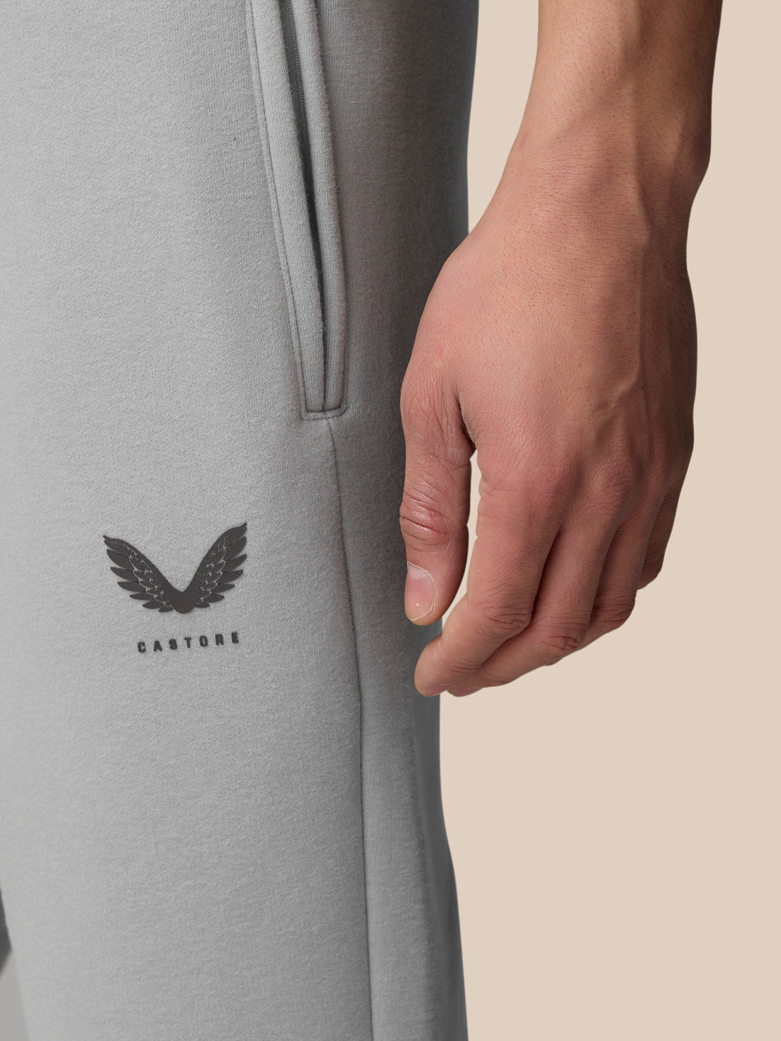 Close up of grey Adapt Fleece jogger leg showing a zip pocket and Castore logo near the thigh.