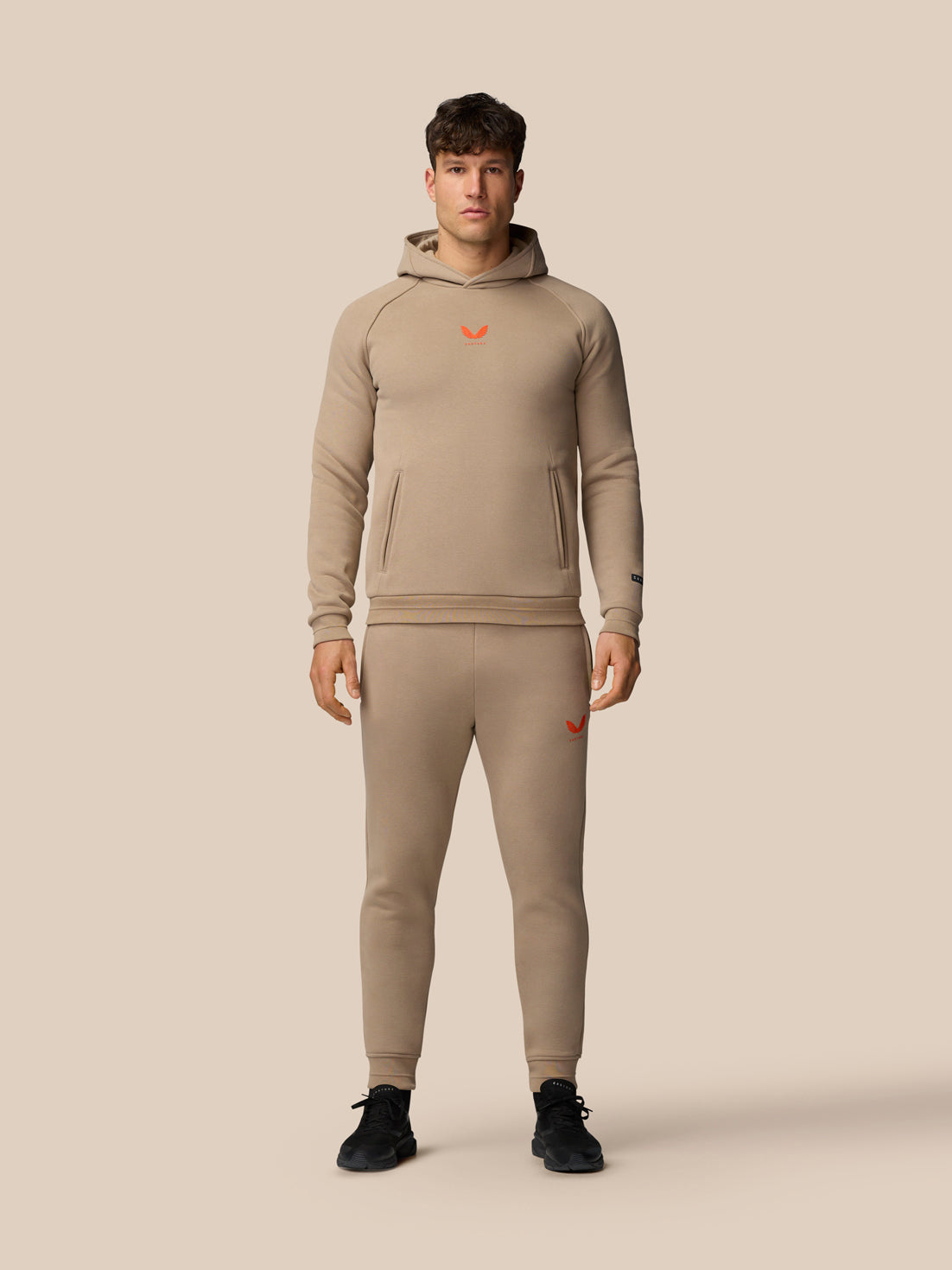 Front view of a male model wearing clay Adapt Fleece Joggers with zip pockets and adjustable drawcord.