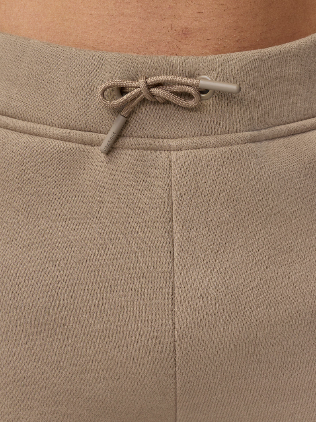 Back waist close up with a tied beige drawcord and Castore branding on the drawcord tips.