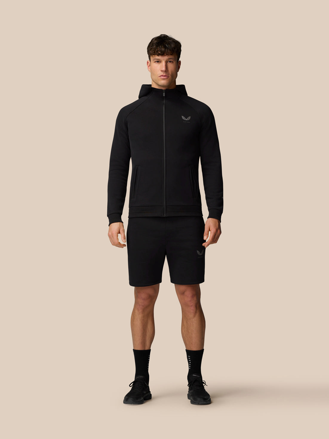 Full-body view of male model in a black Adapt Fleece outfit with a zip hoodie and matching shorts