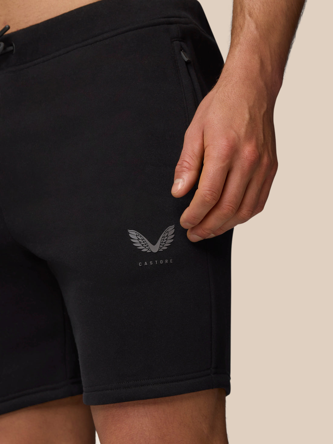 Close-up of black Adapt Fleece Jogger Shorts showing a zip pocket and Castore logo near the hem.