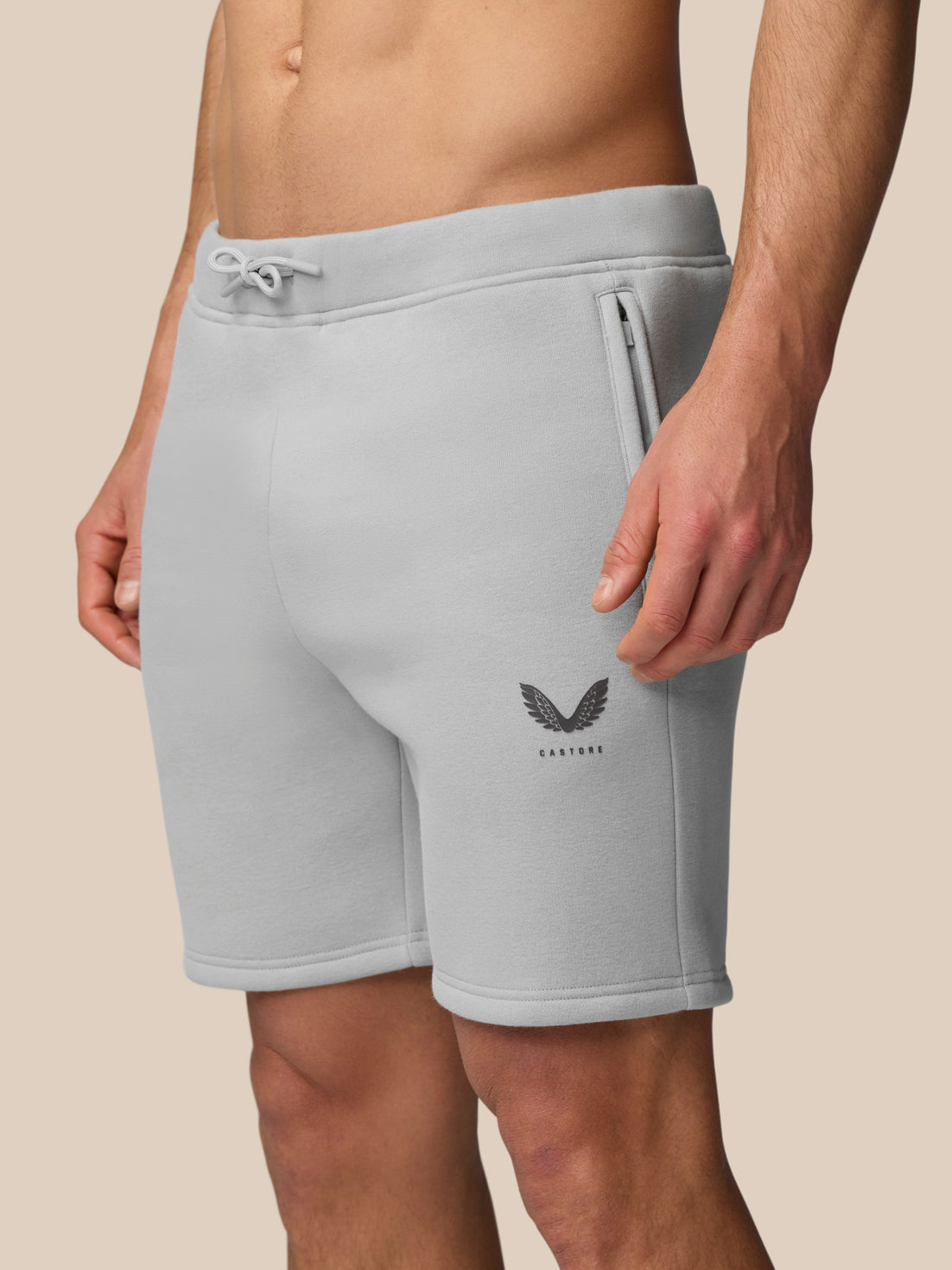 Back view of a man wearing light grey fleece jogger shorts with a rear pocket and Castore logo.