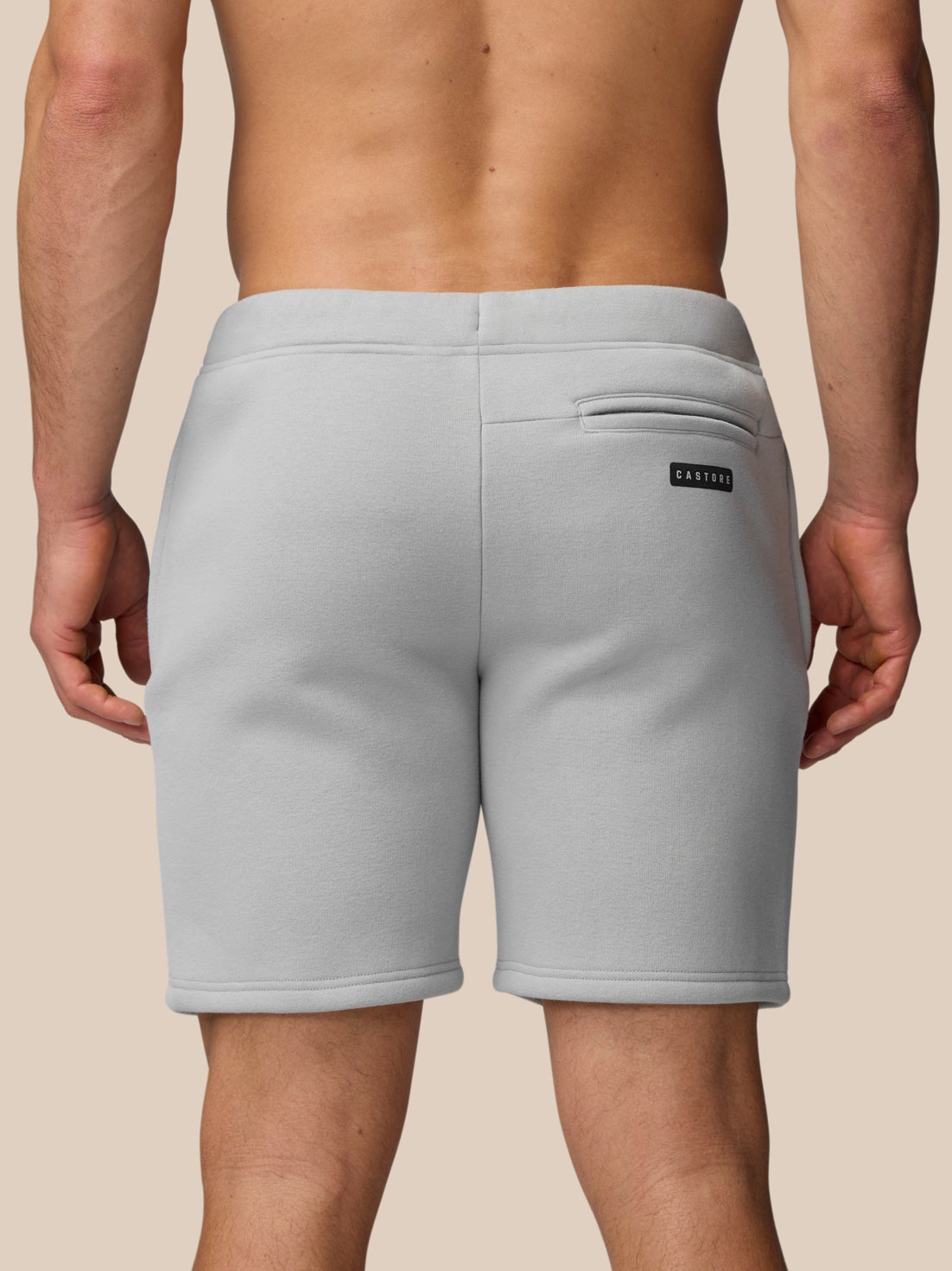 Close-up of light grey fleece shorts showing waistband drawstring and back pocket with Castore logo.