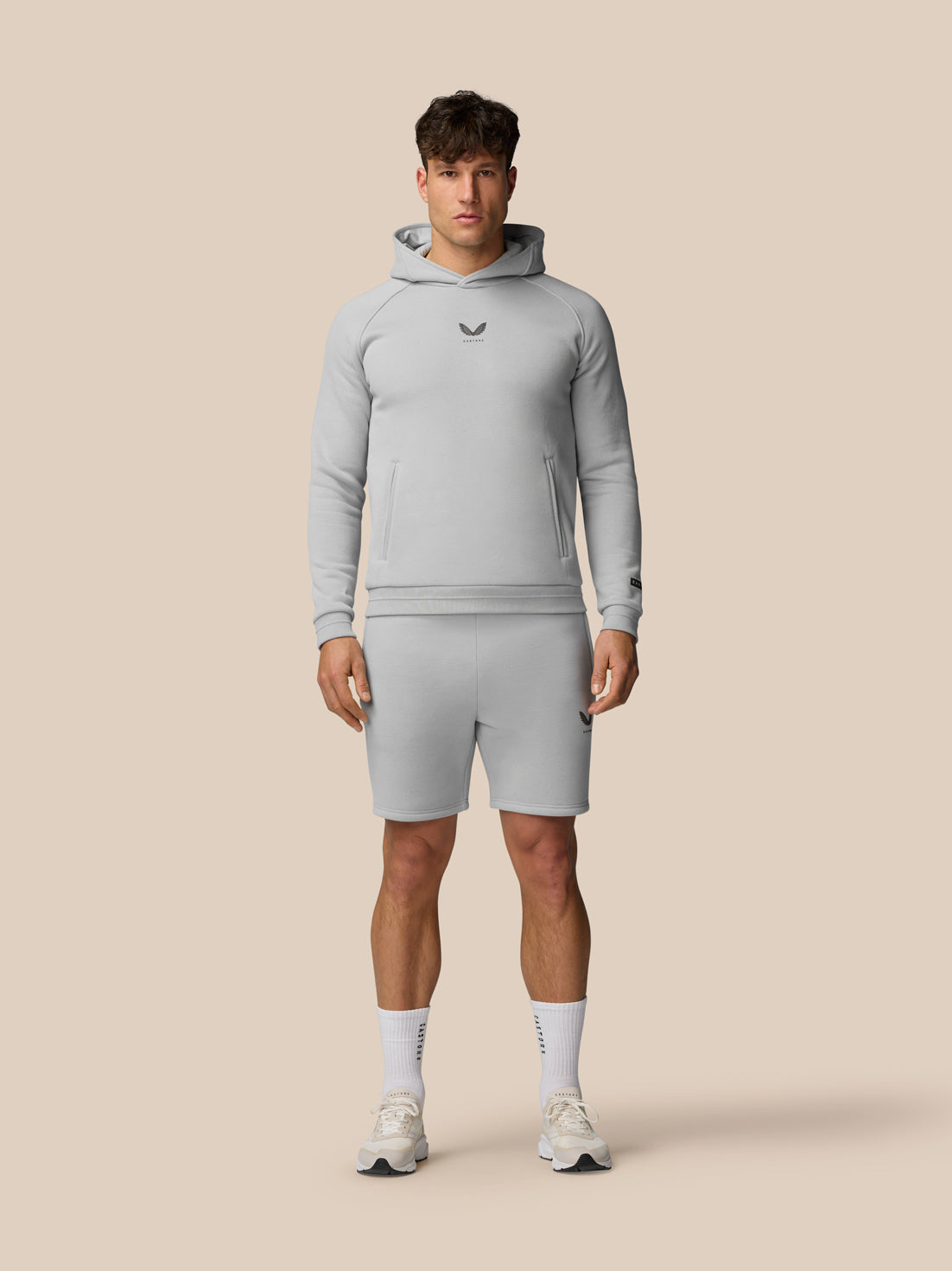 Male model in light grey Adapt Fleece Jogger Shorts with zip pockets and matching hoodie.