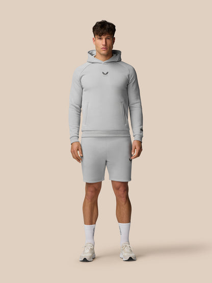Male model in light grey Adapt Fleece Jogger Shorts with zip pockets and matching hoodie.