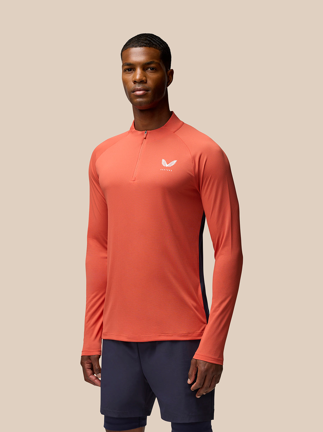 Male model wearing coral orange breathable long sleeve quarter-zip athletic top.