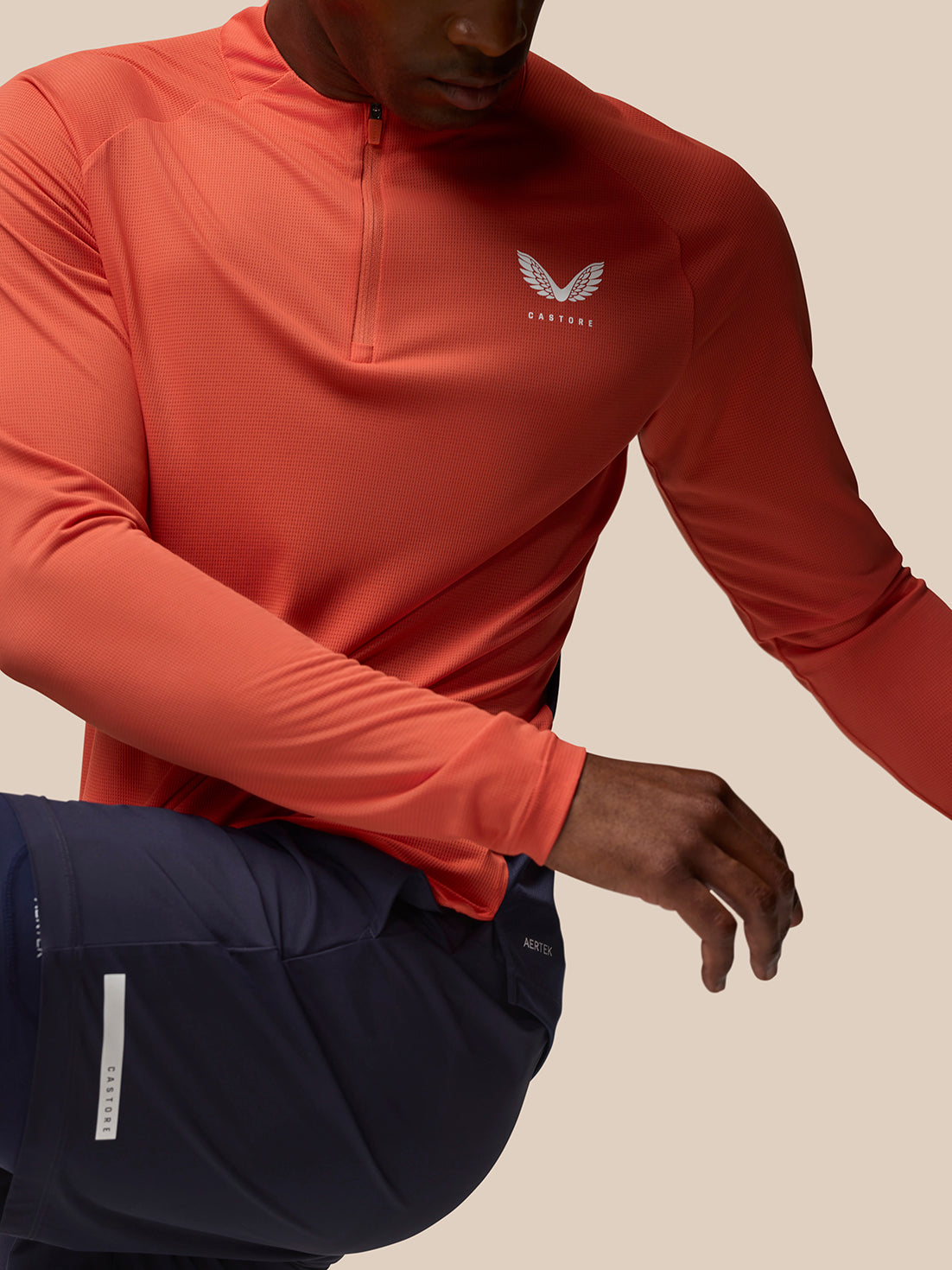Close-up of an orange Breathable 1/4 Zip showing a white Castore logo on the chest.