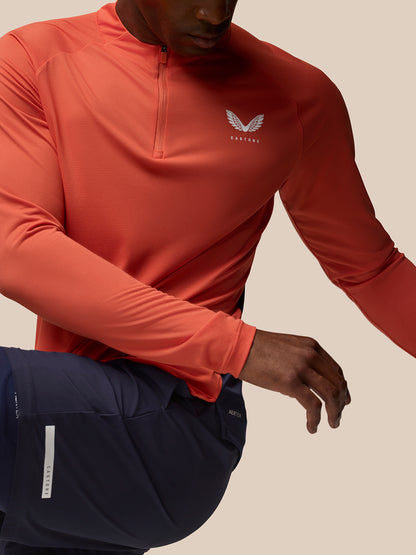 Close-up of an orange Breathable 1/4 Zip showing a white Castore logo on the chest.