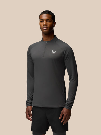 Man wearing gunmetal grey Flow Training long sleeve top with quarter zip and left chest Castore logo.