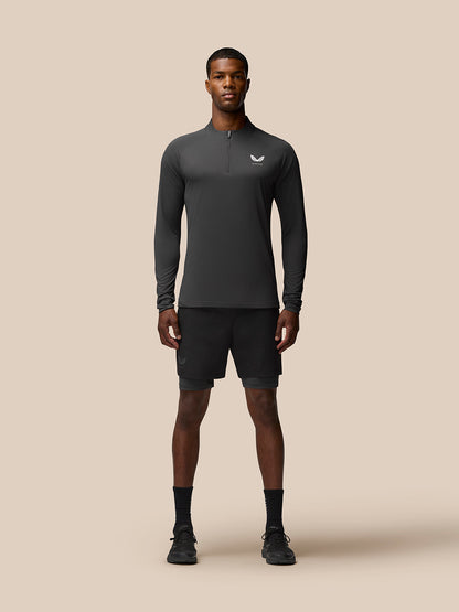 Full-body shot of a man wearing a gunmetal Flow Training quarter-zip top with black shorts