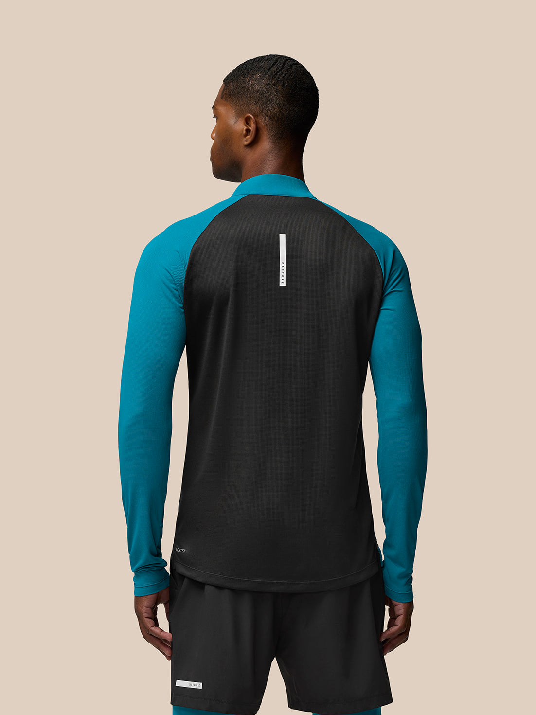 Back view of Flow Training 1/4 Zip Top in dark aqua showing teal sleeves and black back panel.