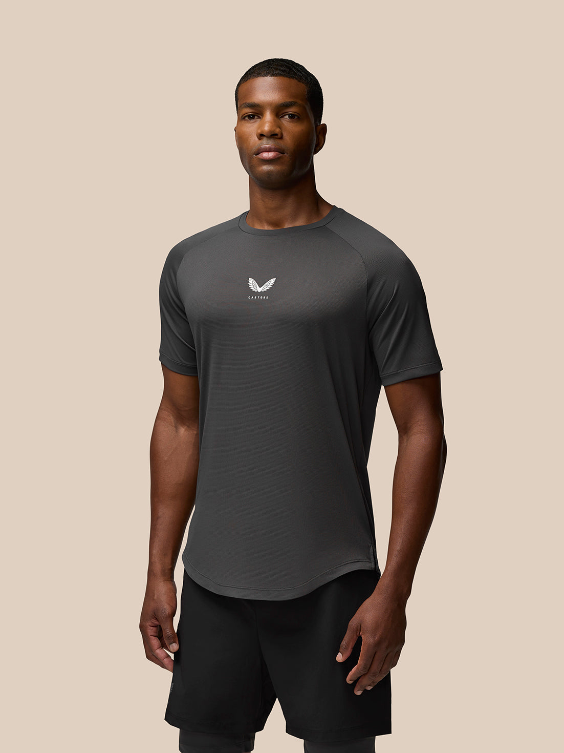 Man wearing charcoal Flow Training T Shirt with a small white Castore logo on the chest.
