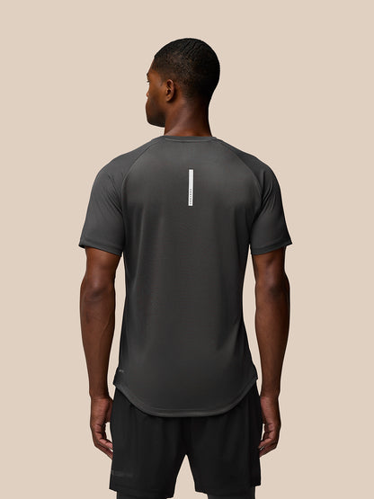 Back view of a man wearing a charcoal Flow Training T-Shirt with a vertical white branding stripe down the center back