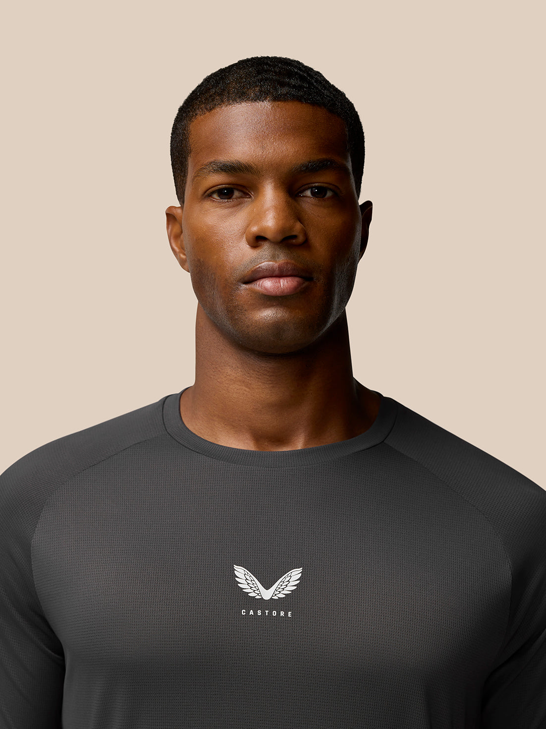 Close-up of a man wearing a charcoal Flow Training T-Shirt showing the Castore logo on the chest