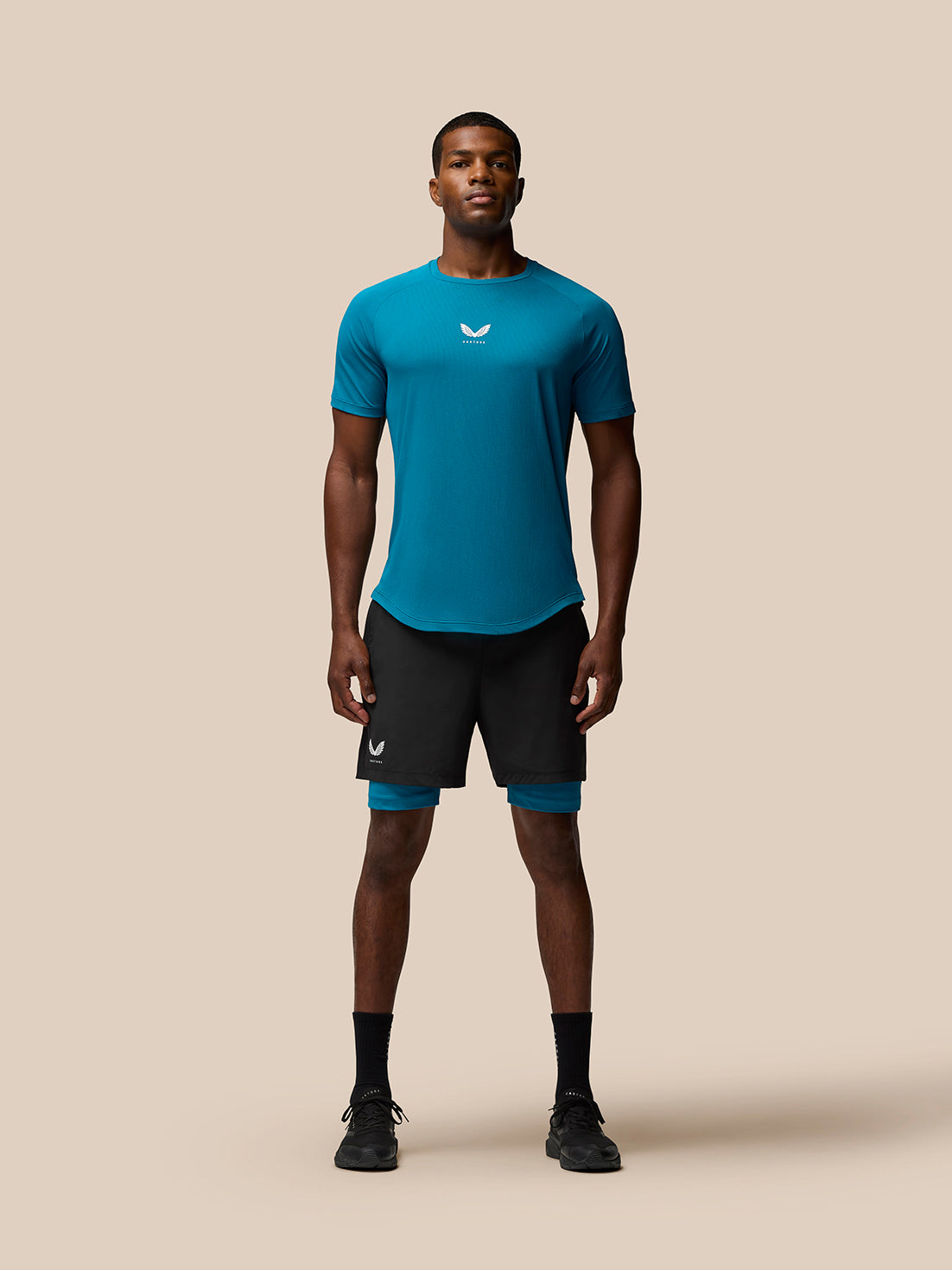 Male model wearing dark aqua Flow Training T-Shirt with center chest logo and curved back hem