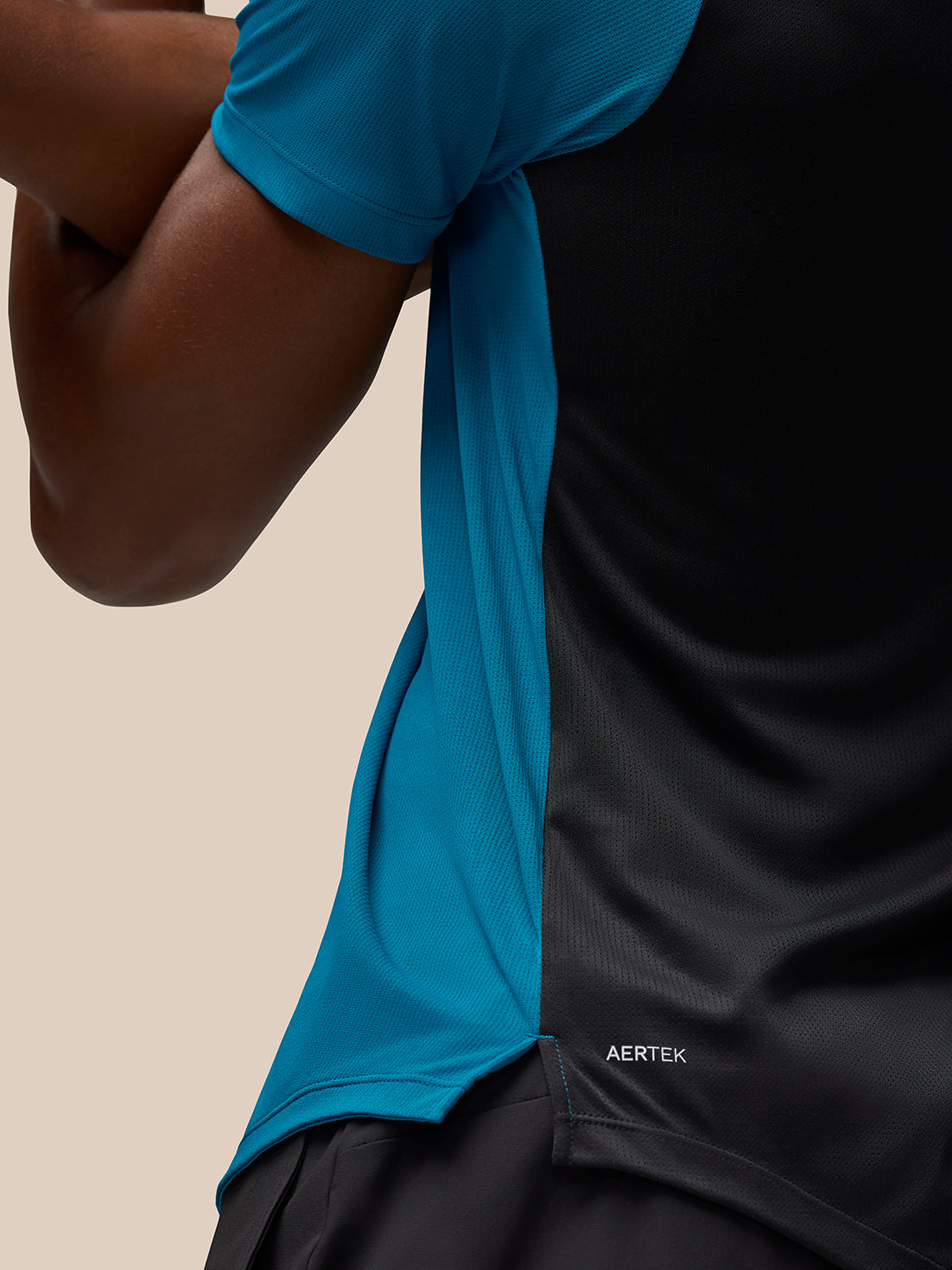 Close-up of Flow Training T Shirt Dark Aqua showing blue side panel and AerTek branding at bottom left back
