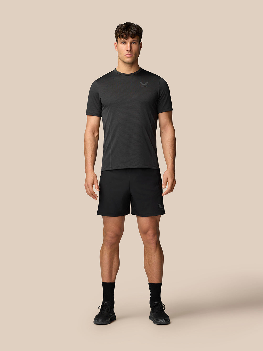 Male model wearing black Apex training T-shirt and matching shorts, standing facing the camera.