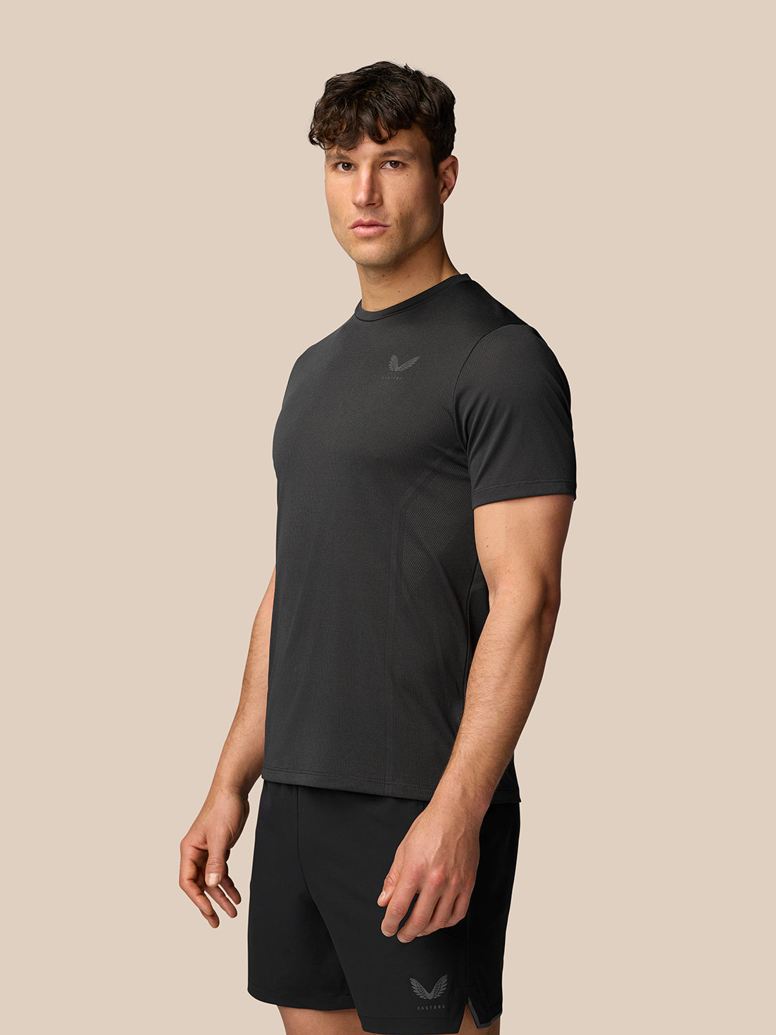 Three-quarter view of a male model in a black Apex Training T-Shirt showing chest logo and breathable fabric.