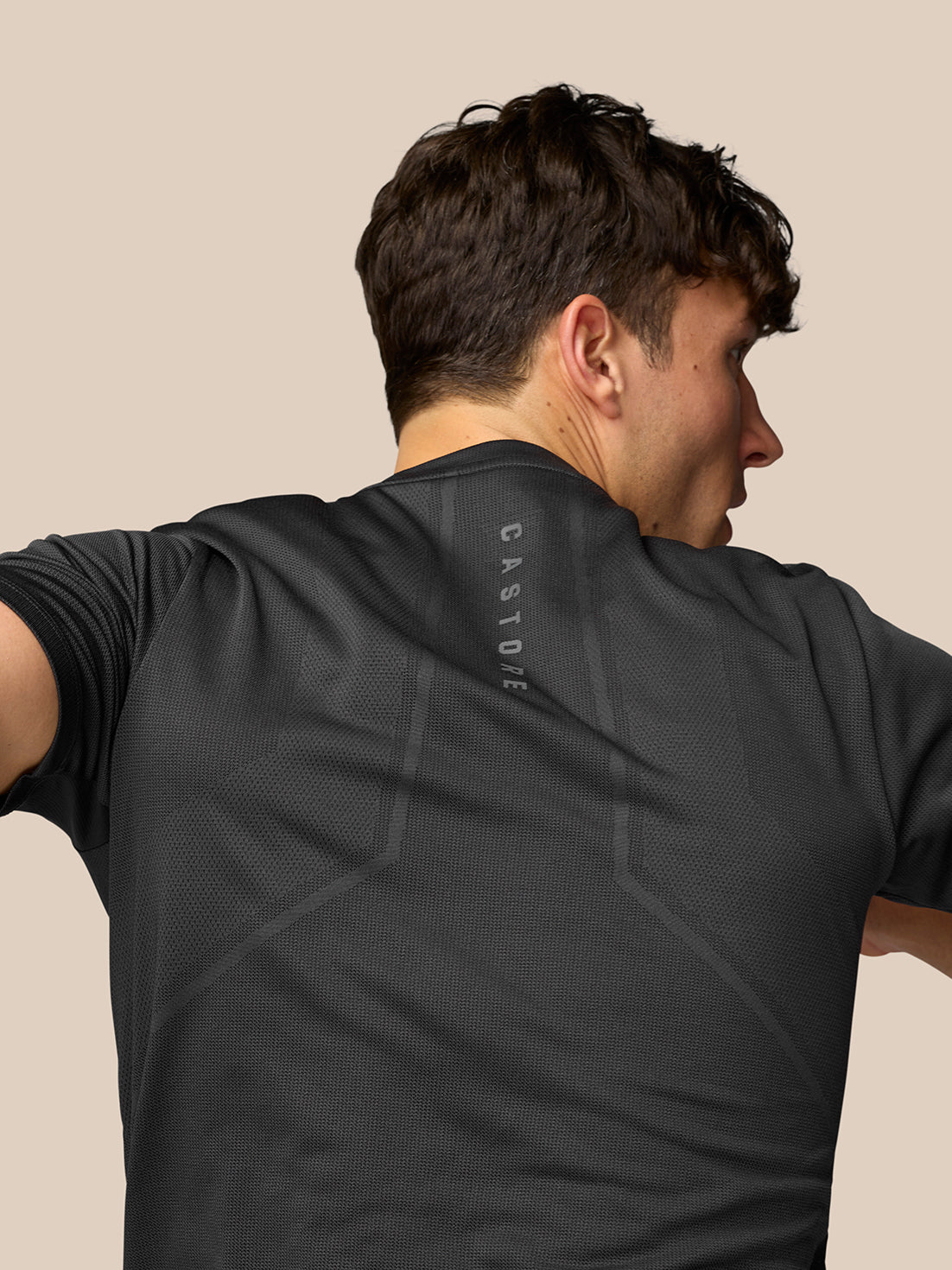 Back view of a male model in a black Apex Training T-Shirt with vertical Castore branding along the upper back.