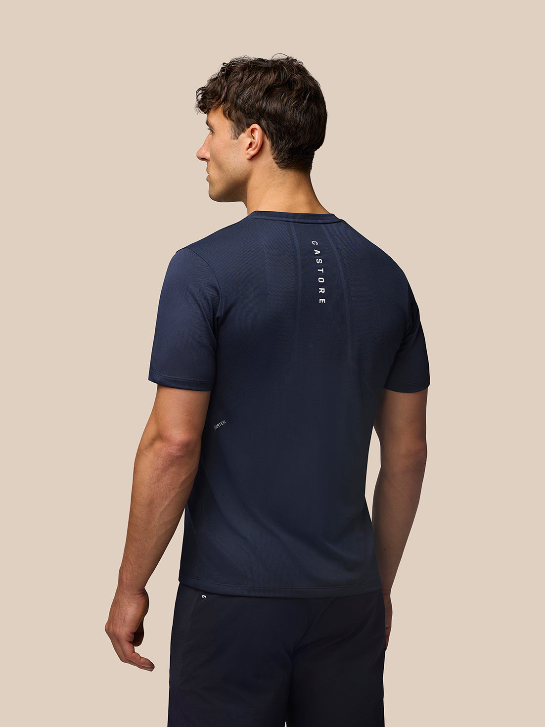 Back view of a man in Midnight Navy Apex Training T Shirt, showing vertical Castore branding along the upper back