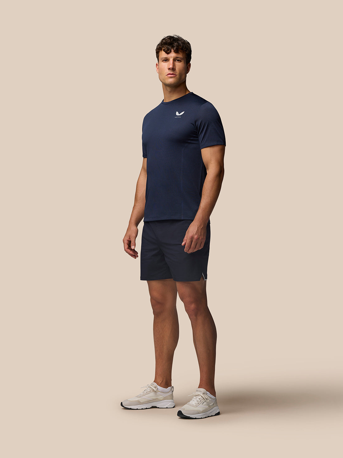 Male model wearing Apex Training T-Shirt Midnight Navy with navy shorts and white sneakers