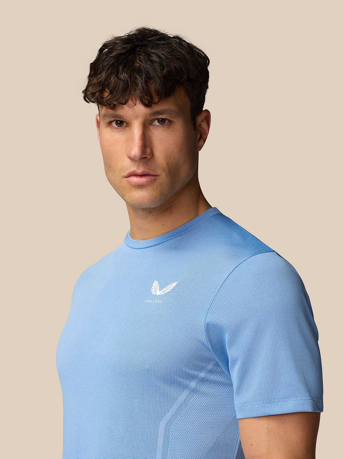 Male model wearing sky blue Apex Training T-Shirt with breathable mesh knit and reflective Castore logo on the chest.