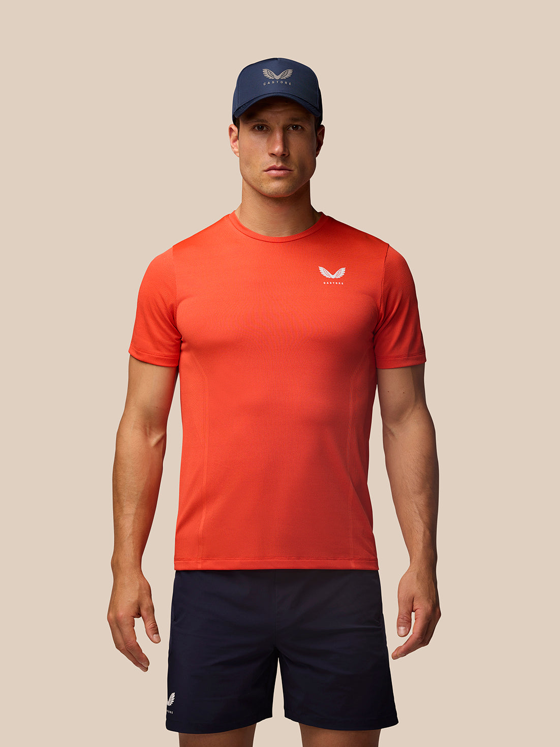 Man wearing red Apex Training T Shirt with white chest logo, navy cap and navy shorts