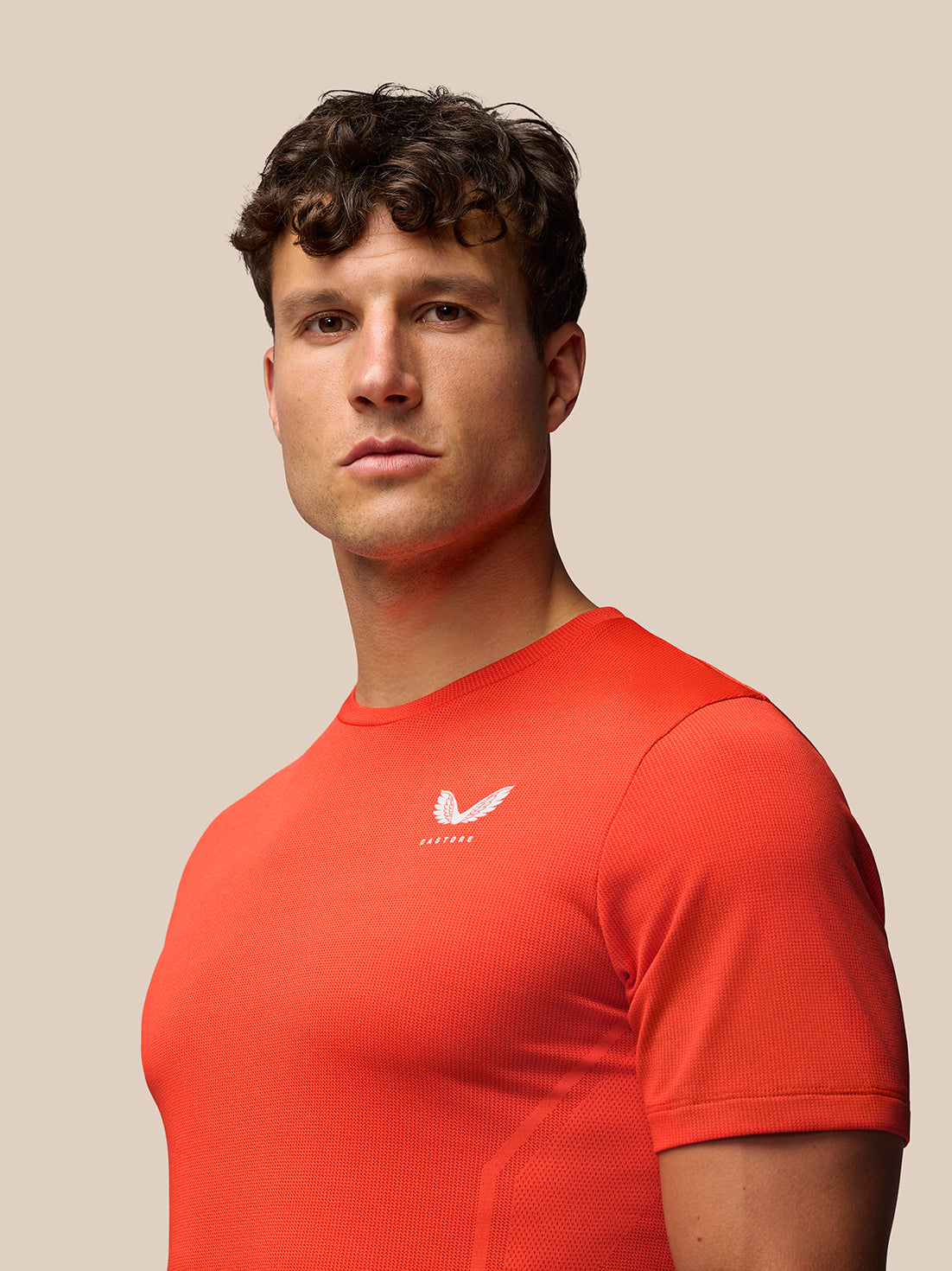 Man wearing red Apex Training T Shirt with Castore logo on the chest and Aertek branding on the back