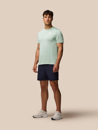 Man wearing mint green Apex Short Sleeve Engineered Knit T Shirt with navy shorts and white sneakers.