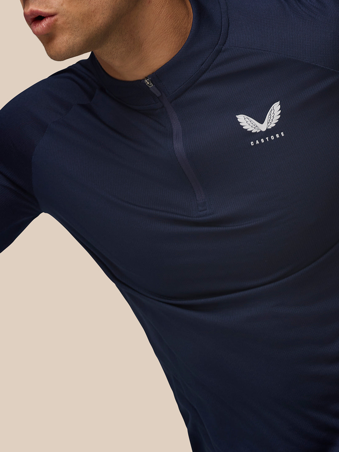Close up of navy Apex Training quarter zip top showing zip at the collar and Castore logo on the left chest.