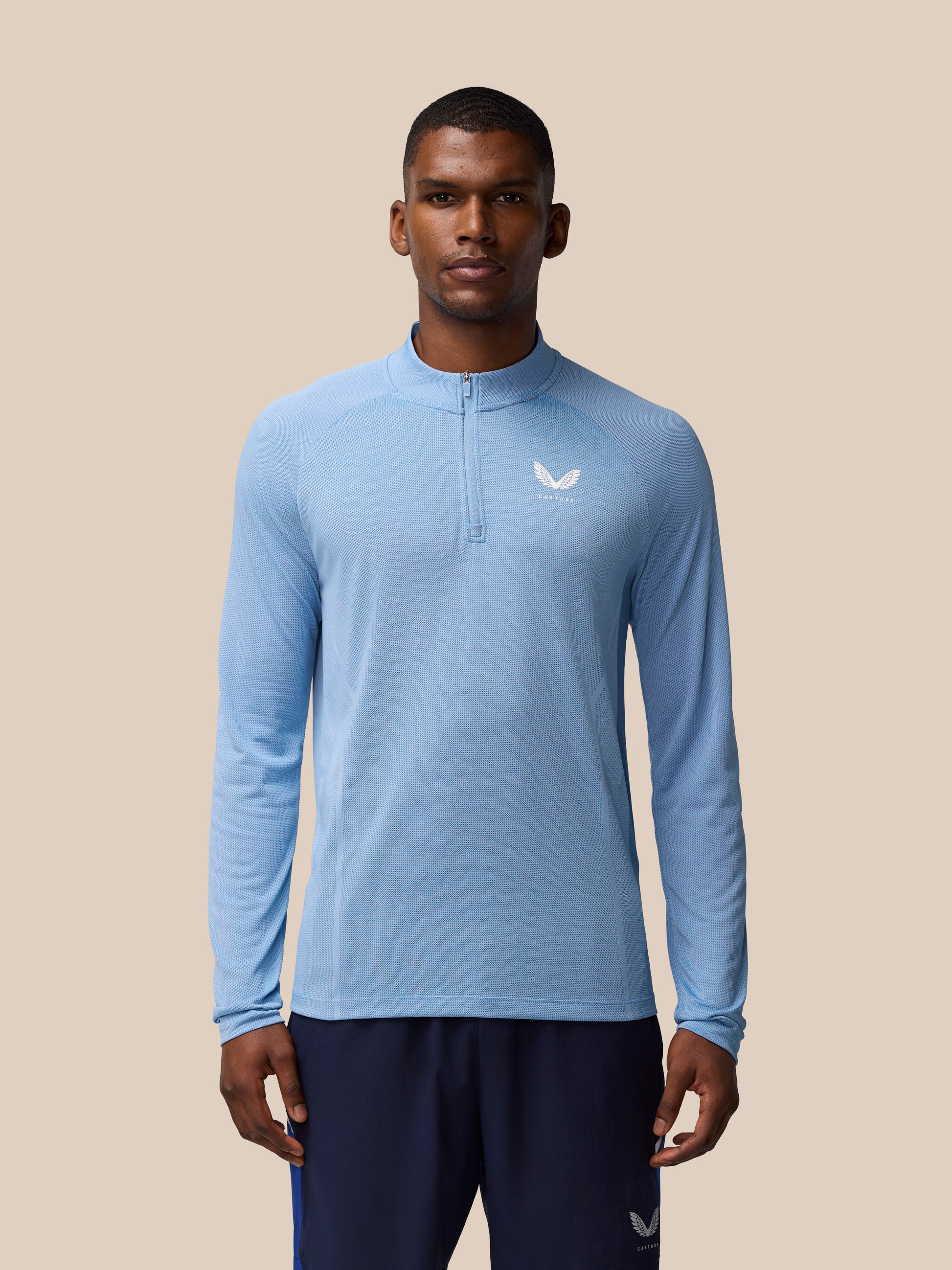 Male model wearing sky blue Apex Training quarter-zip top with textured knit fabric and left chest logo.
