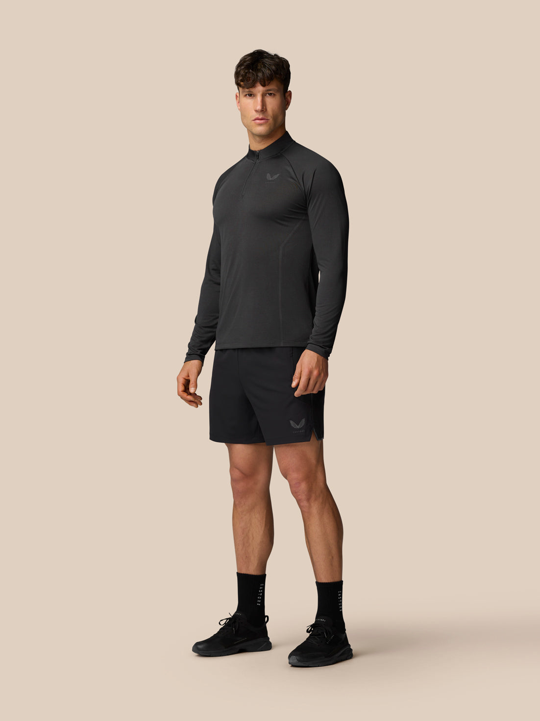 Male model in dark Apex Training long sleeve 1/4 zip top with logo on the chest