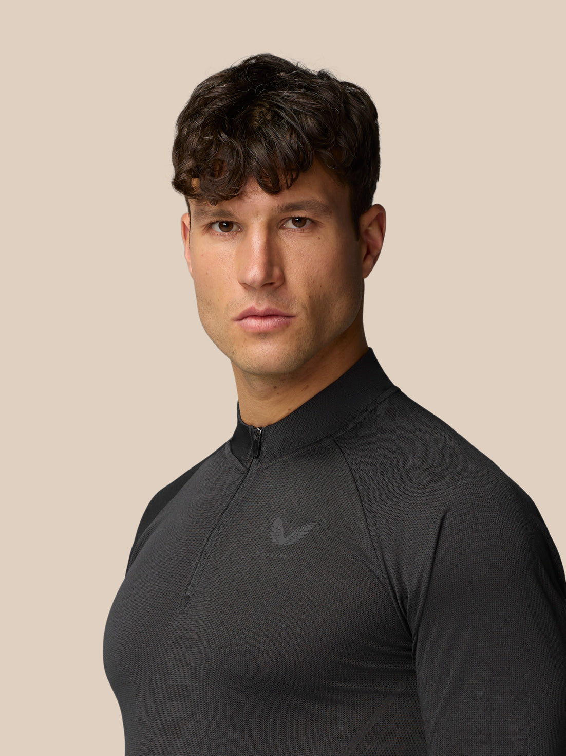 Male model wearing Apex Training 1/4 Zip Top in black gunmetal, three quarter view highlighting knit texture and zip collar