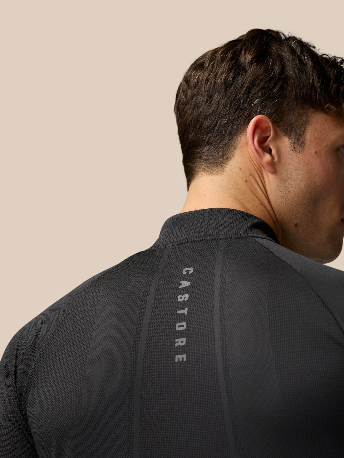 Back view of a man in black gunmetal Apex Training 1/4 Zip Top with mesh panels and Castore branding along back