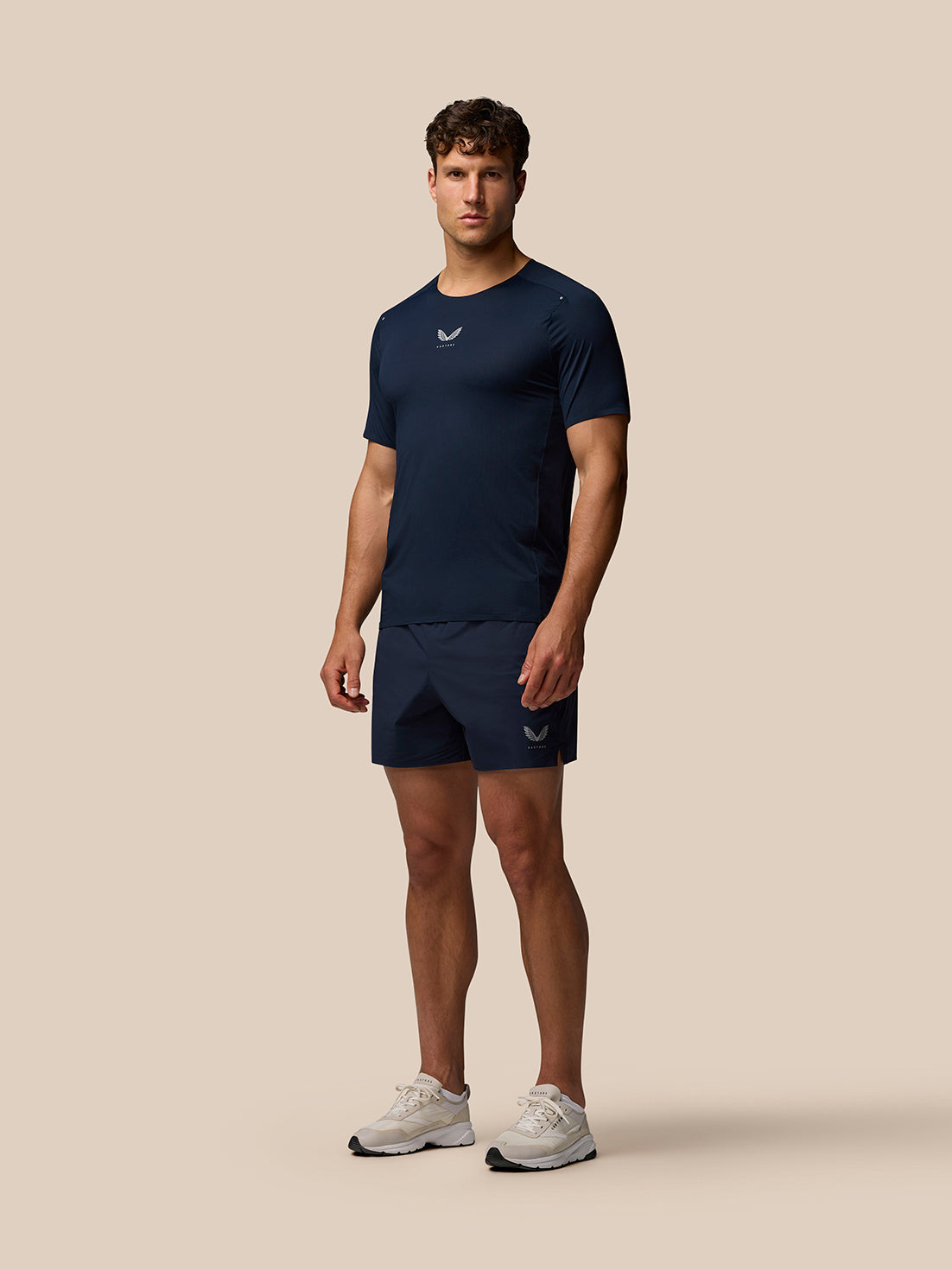 Full body shot of male model in navy Zone Training T-Shirt with matching shorts and light sneakers