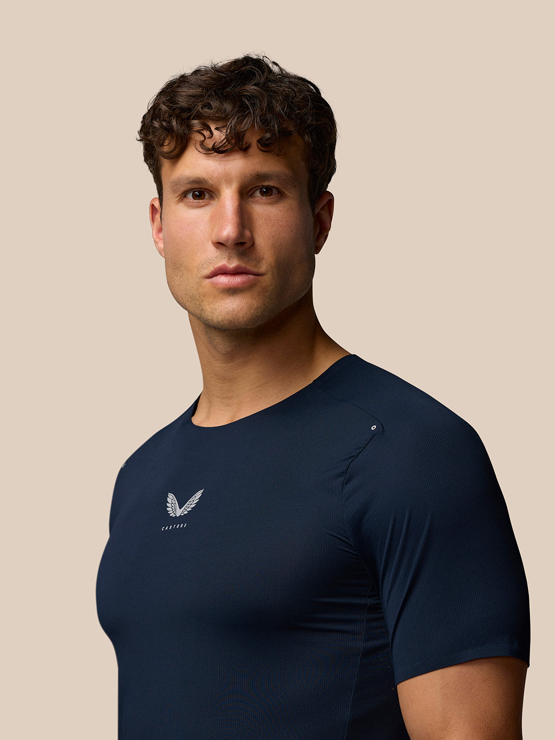Male model wearing navy Zone Training T-Shirt with Castore logo on chest, close-up of torso