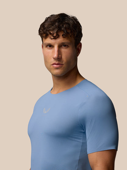 Male model wearing blue Zone Training T-Shirt with crew neck against a beige background