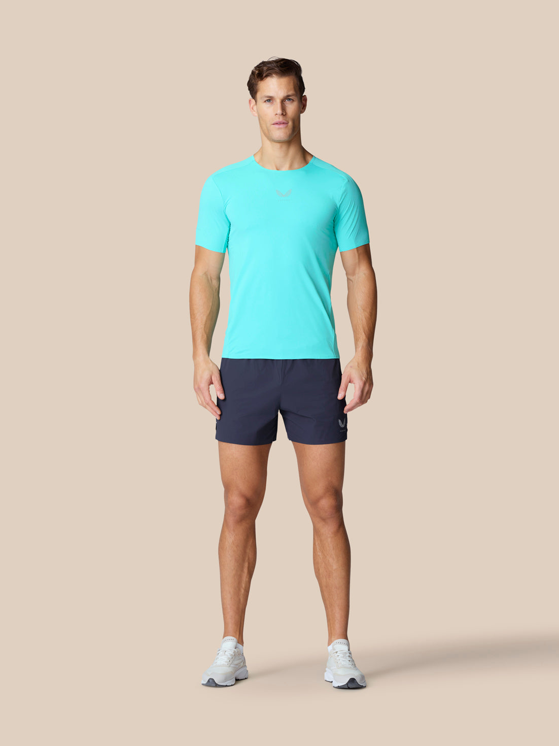 Full-body view of a model wearing light aqua Zone Training T Shirt with navy shorts
