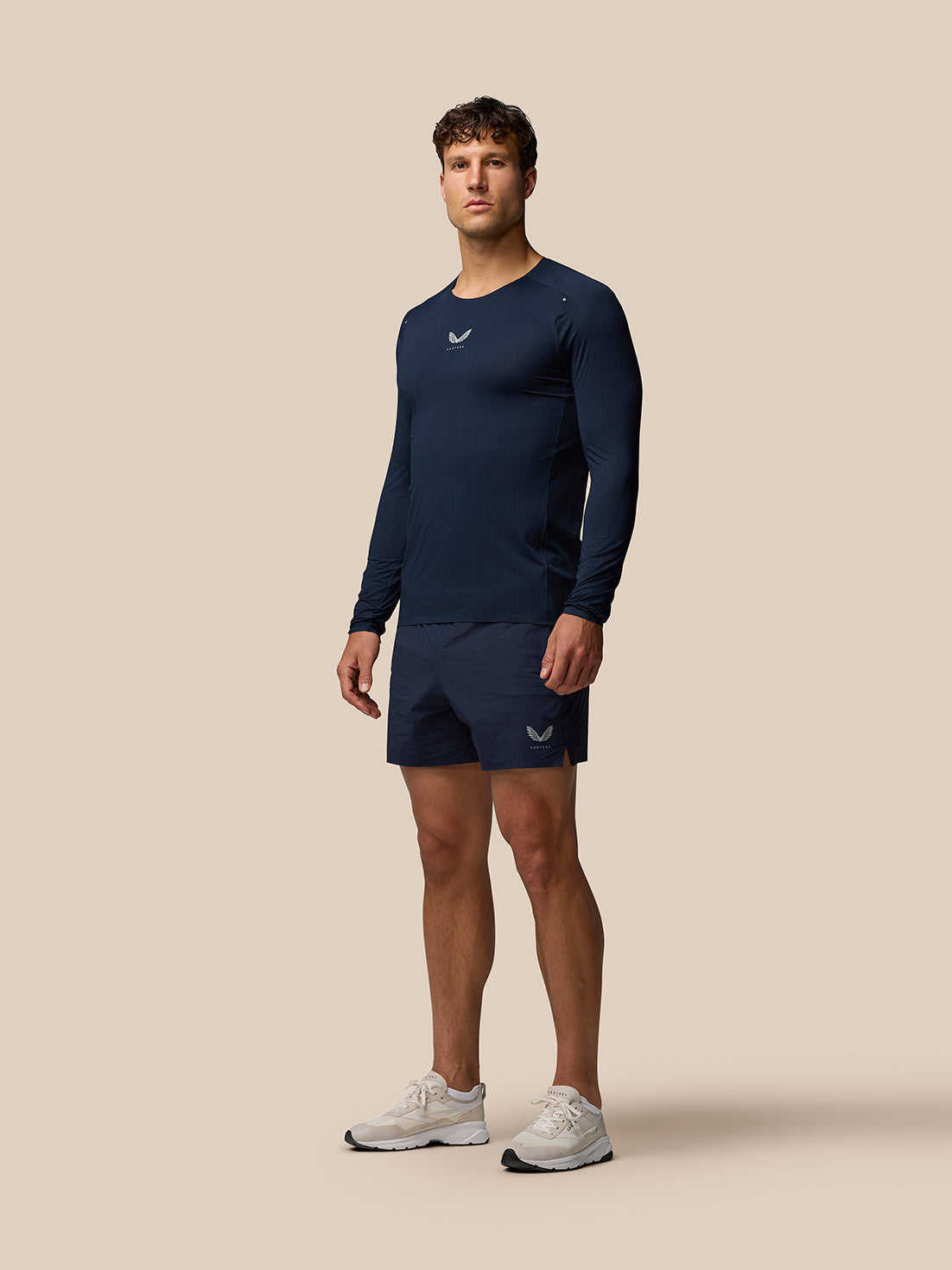 Male model wearing navy Zone Training Long Sleeve Ventilation T Shirt with reflective branding on chest and cuffs
