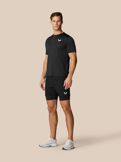 Full body shot of male model wearing Flow Training T-Shirt Black with matching shorts, honeycomb pattern and Castore logos on chest and leg.
