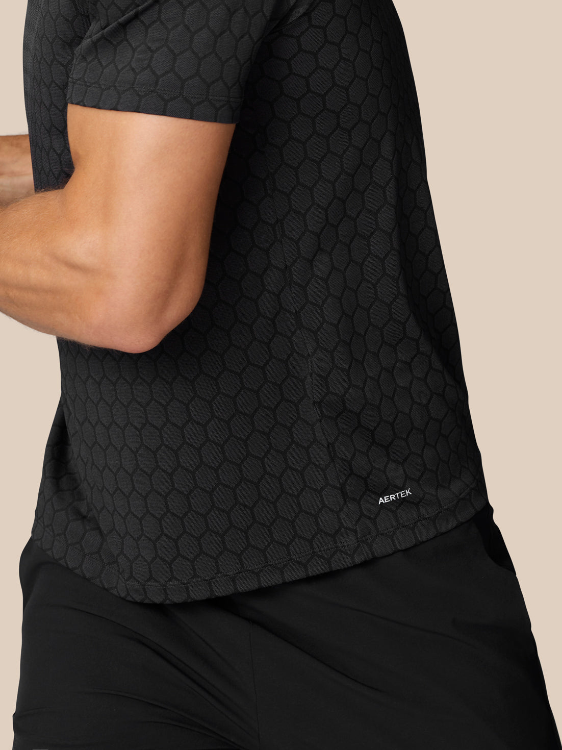 Side back view of black Flow Training T Shirt showing honeycomb knit with AERTEK branding at the lower hem
