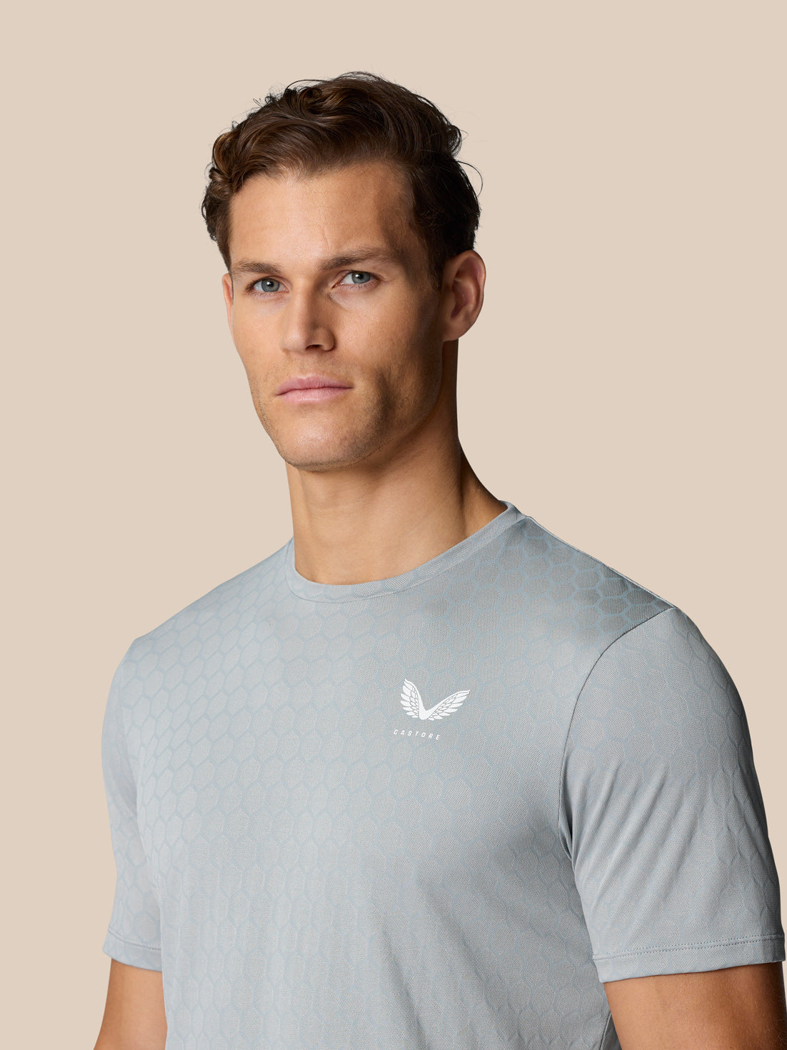 Male model wearing Flow Training T-Shirt Grey with honeycomb pattern and Castore logo on the chest