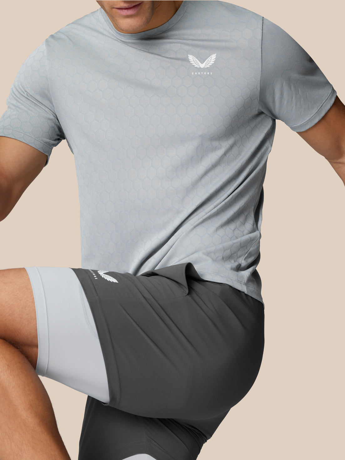 Close-up of a man in a light grey Flow Training T Shirt with hexagonal pattern and Castore logo on the chest.