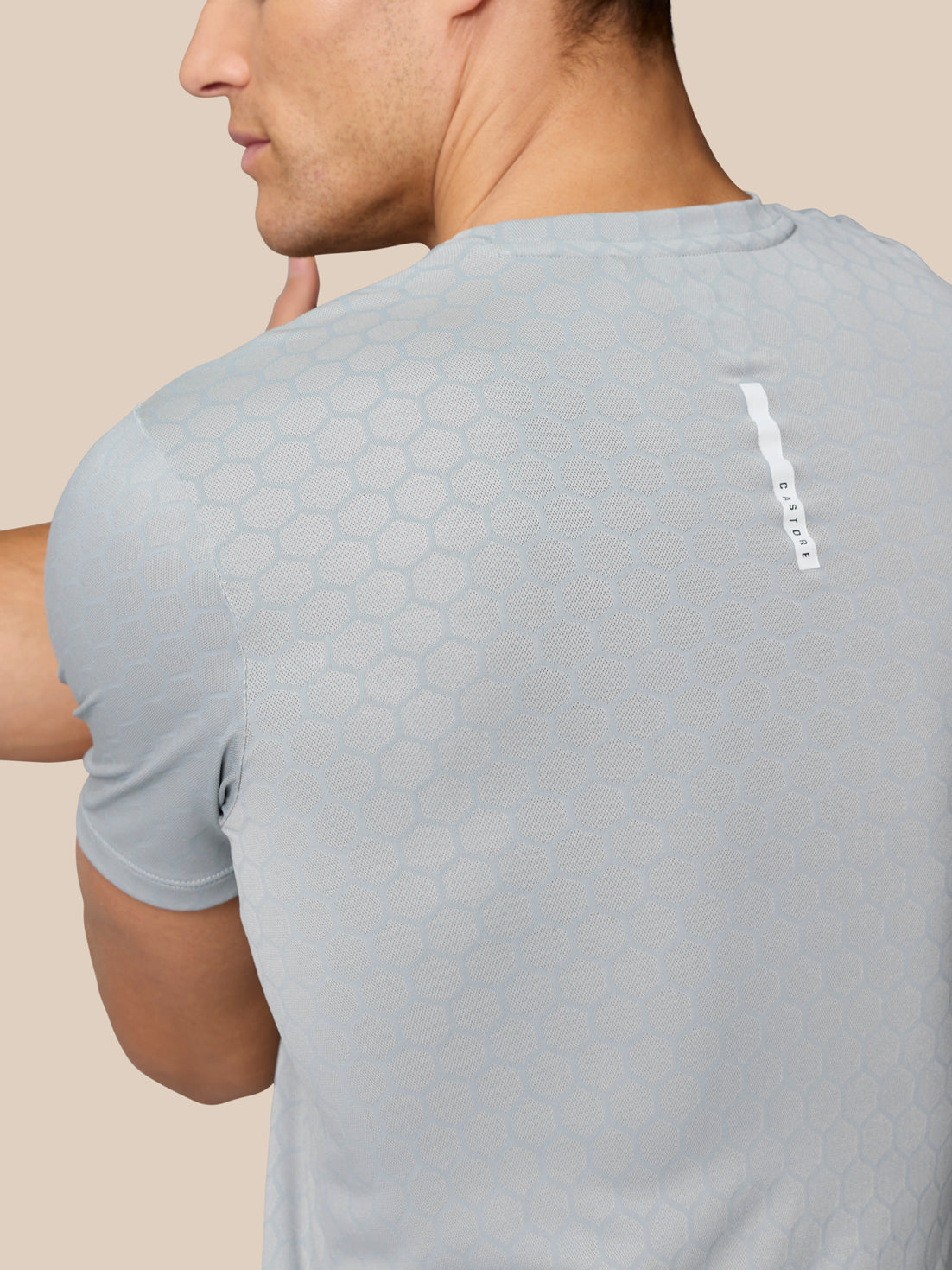 Back close-up of Flow Training T Shirt showing hexagonal knit pattern and a vertical Castore label on the upper back.
