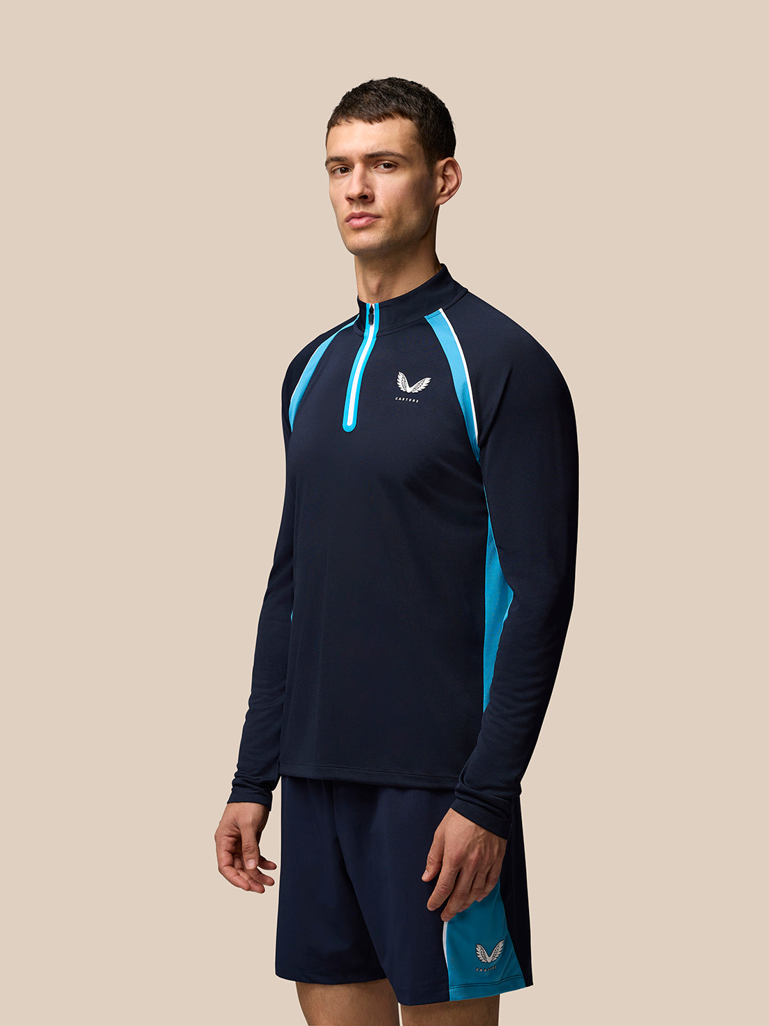 Male model wearing navy tennis long sleeve top with light blue piping and front quarter zip