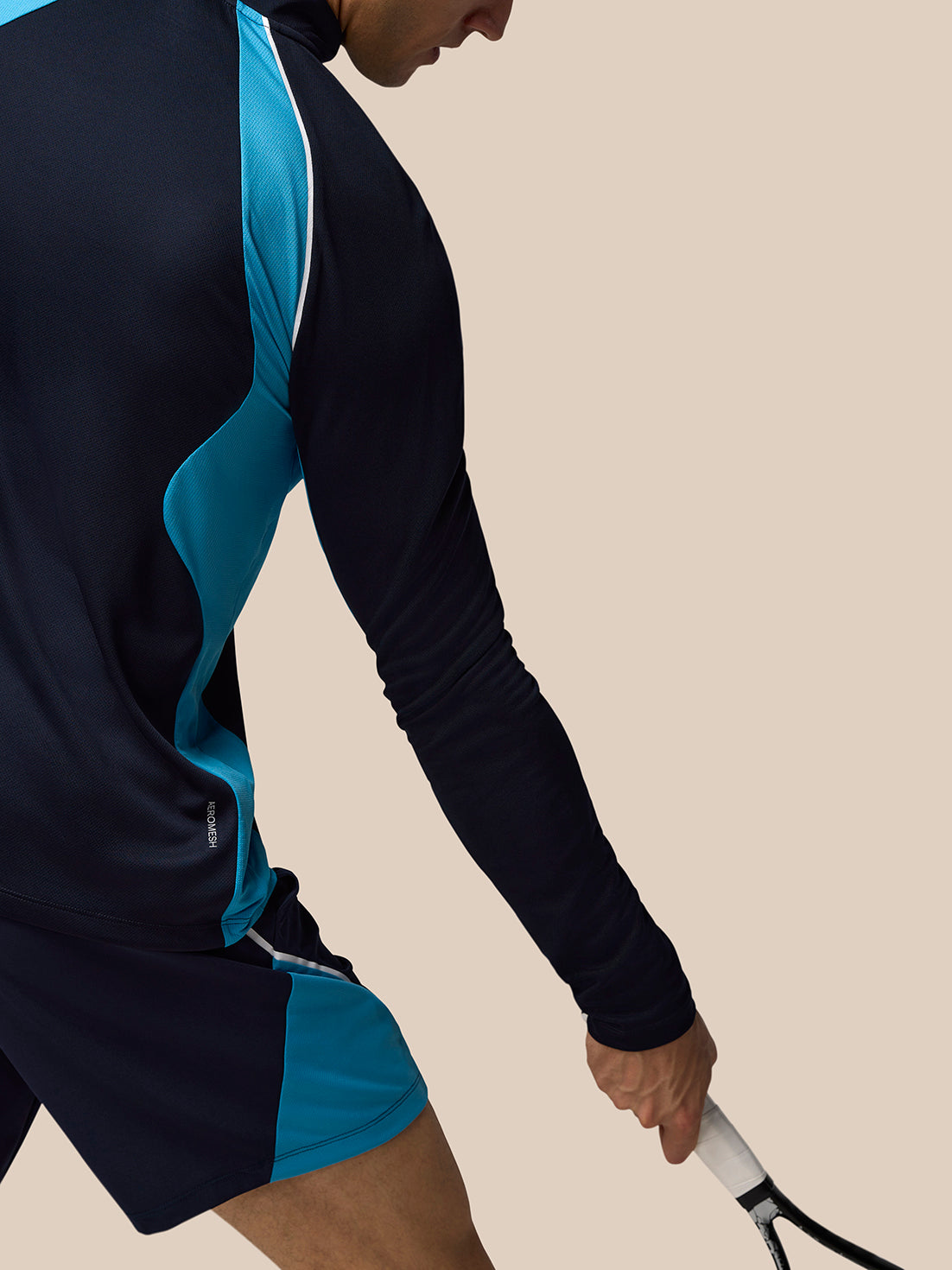 Side view of navy tennis top with teal side panel and white trim and Aeromesh branding at hem