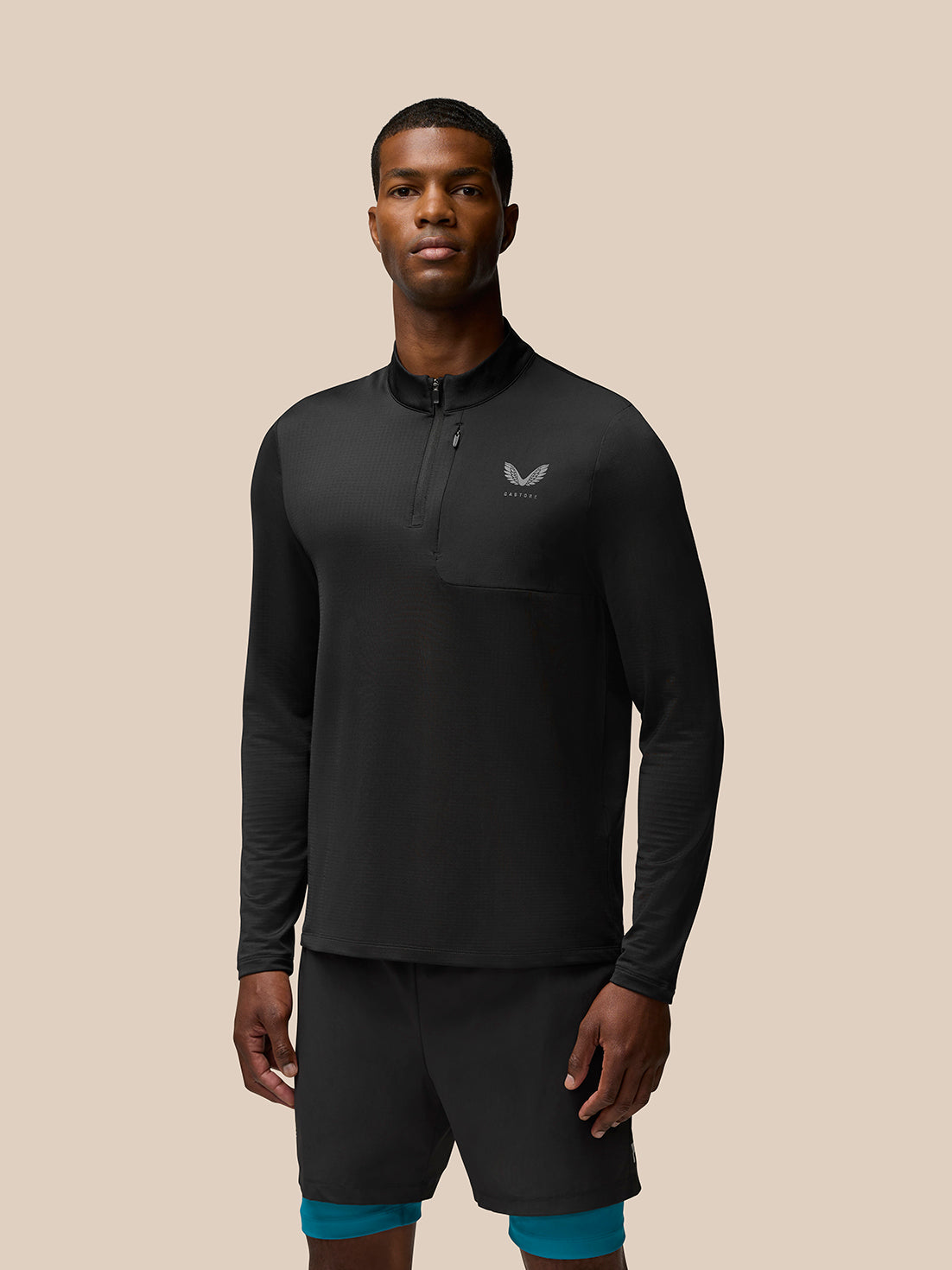 Model wearing Flow Sweatshirt in black with funnel collar quarter zip chest pocket and Castore branding on left chest